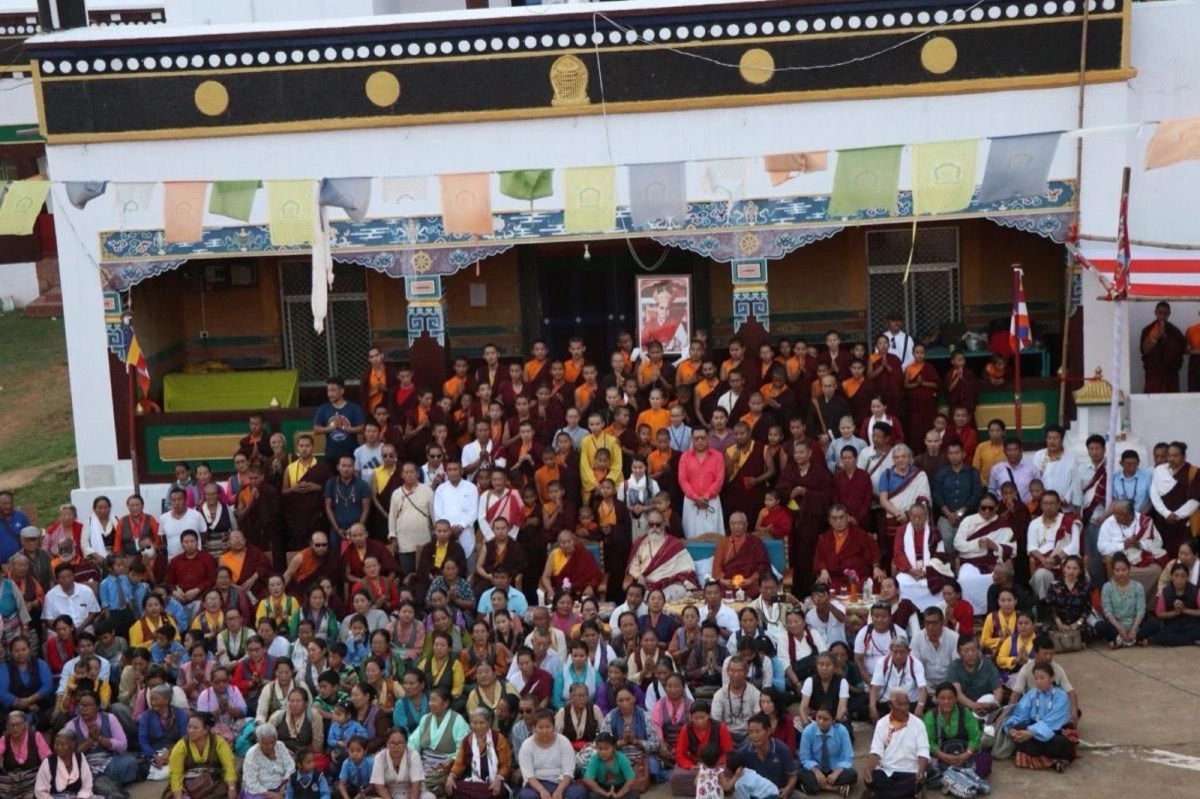 Large gathering of monks and lay practitioners in front of the monastery