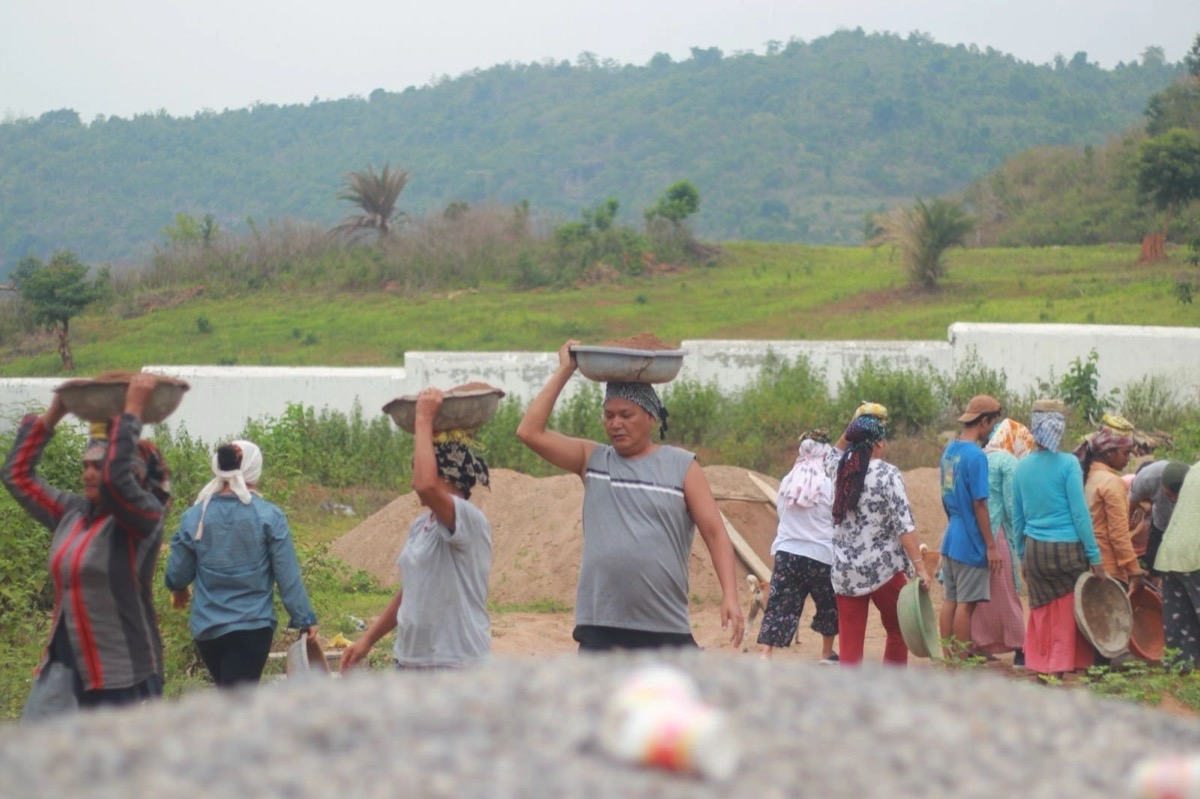 Local workers carrying bowls of gravel on their heads at the construction site