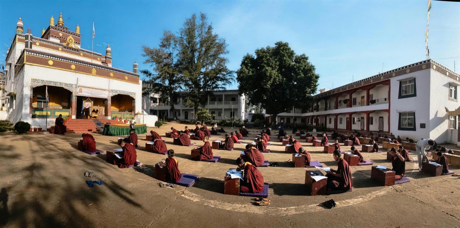 Monks seated in rows in the courtyard of Dundul Raptenling Monastery